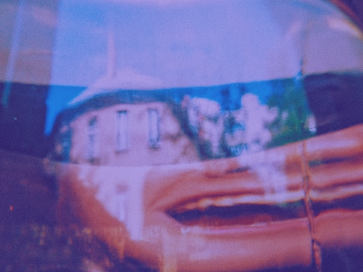 A building distorted and warped behind a sheet of rippled plastic, tinted blue and orange